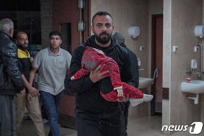 12일(현지시간) 가자지구 중부 데이르 알 바라에서 한 남성이 아기를 안고 병원으로 들어서고 있다. 2024.03.12 ⓒ AFP=뉴스1 ⓒ News1 정지윤 기자