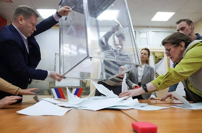 17일(현지시간) 러시아 대통령 선거가 종료된 직후 선거관리위원회 직원들이 투명한 투표함에서 투표용지를 꺼내고 있다. 투명한 투표함은 이번 러시아 대선이 비민주적이라는 비판을 받는 이유 가운데 하나다. [사진=로이터연합]