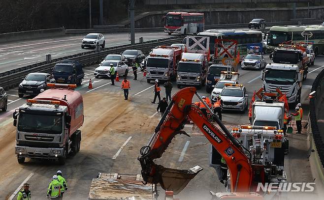[성남=뉴시스] 김근수 기자 = 19일 경기 성남시 경부고속도로 판교IC 인근 서울 방면 도로에서 한국도로공사 직원들이 도로에 쏟아진 잔해물을 정리하고 있다. 소방과 경찰에 따르면 이날 오전 6시쯤 경기 성남시 인근 경부고속도로 판교IC 양재방면 도로에서 A(60대)씨가 몰던 25톤 트레일러와 B(50대)씨가 운전하던 25톤 덤프트럭이 충돌했다. 2024.03.19. ks@newsis.com