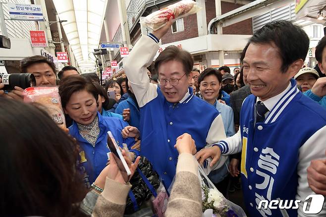 이재명 더불어민주당 대표가 24일 서울 잠실 새마을전통시장을 방문해 지지자로부터 빵과 꽃다발을 전달받고 있다. (공동취재) 2024.3.24/뉴스1 ⓒ News1 김도우 기자
