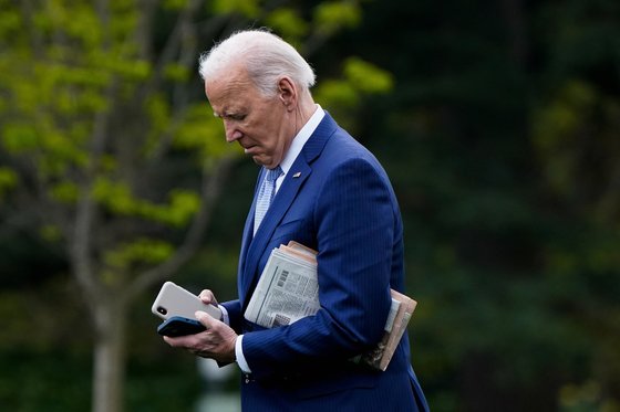 조 바이든 미국 대통령이 22일 미국 워싱턴 백악관을 떠나면서 신문과 휴대전화를 들고 마린 원을 향해 걸어가고 있다. 로이터=연합뉴스