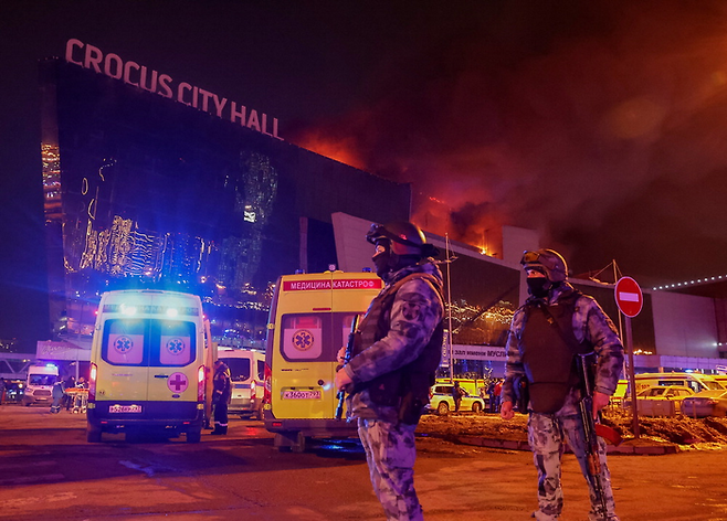 지난 22일 밤(현지시간) 총격 테러와 화재가 발생한 러시아 모스크바 크로커스 시티홀 콘서트장에서 소총으로 중무장한 당국 요원이 주차장 일대를 수색하고 있다. [로이터=연합뉴스]