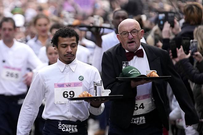 24일(현지시각) 프랑스 파리에서 열린 ‘웨이터 경주 대회’ 참가자들이 쟁반을 손에 들고 도심을 지나고 있다. 파리/AP 연합뉴스