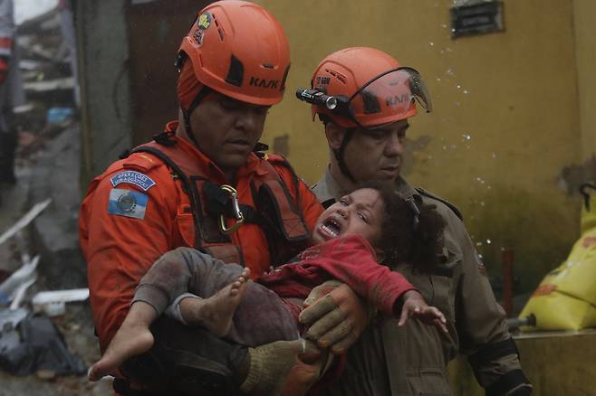 23일(현지시간) 브라질 리우데자네이루주 페트로폴리스에서 폭우로 무너진 집에서 구조된 4세 여아를 구급대원들이 옮기고 있다. AP=연합뉴스