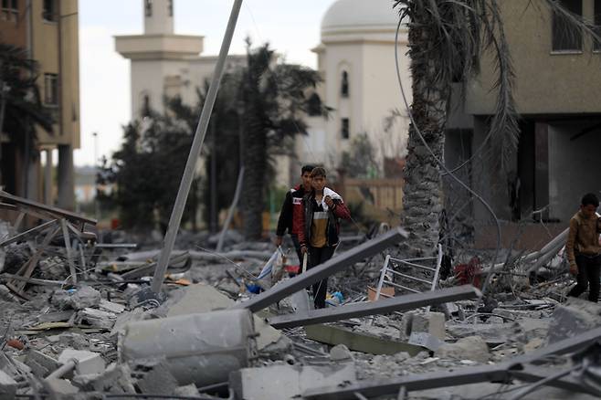 팔레스타인 가자지구 주민들이 25일(현지시간) 이스라엘군 폭격으로 무너진 건물 잔해 사이를 걸어가고 있다. 신화연합뉴스