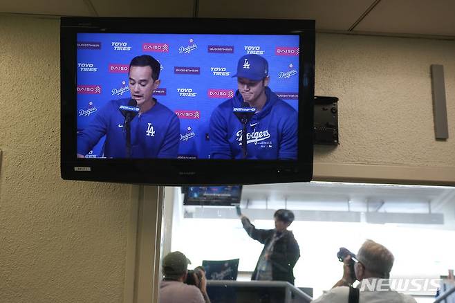 [로스앤젤레스=AP/뉴시스] 로스앤젤레스 다저스의 오타니 쇼헤이(오른쪽)가 25일(현지시각) 미 캘리포니아주 로스앤젤레스의 다저스타디움에서 새 통역사 윌 아이레튼과 함께 기자회견 하는 모습이 모니터로 송출되고 있다. 오타니는 “(통역사) 미즈하라가 도박 빚을 갚기 위해 내 계좌에서 돈을 훔친 것”이라며 “내게 거짓말을 했기 때문에 난 전혀 몰랐다”라고 입장을 밝혔다. 2024.03.26.