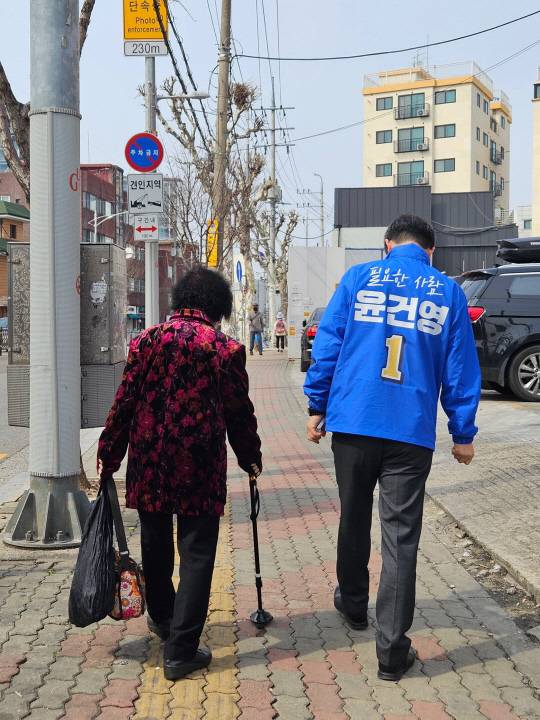 윤건영 더불어민주당 서울 구로을 후보가 27일 대로변에서 한 어르신과 동행하며 근황을 주고 받고 있다.<윤건영 후보 제공>