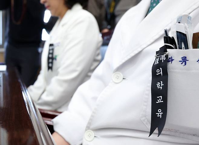 근조리본 달고…간담회 참석한 의사들 강원 춘천시 강원대학교병원 의사들이 27일 병원에서 이주호 부총리 겸 교육부 장관이 참석한 가운데 열린 의대·병원 현장 간담회에서 ‘근조 의학교육’ 리본을 단 채 자리에 앉아 있다. 연합뉴스
