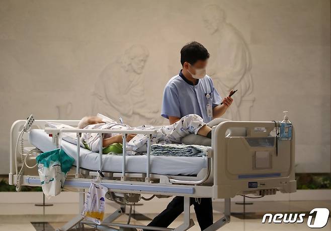 정부의 의대 증원에 반발하는 전공의 집단이탈과 의대교수 사직서 제출로 의료공백이 불가피해진 가운데 27일 대구의 한 대학병원에서 의료진이 환자의 병상을 밀며 예수가 제자들의 발을 씻겨주는 세족례를 담은 부조상 앞을 지나고 있다. 2024.3.27/뉴스1 ⓒ News1 공정식 기자