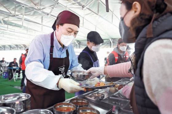윤석열 대통령이 27일 서울 명동성당 내 무료 급식소인 '명동밥집'에서 봉사활동을 펼치며 빈 테이블에 놓을 식판에 배식을 받고 있다.연합뉴스