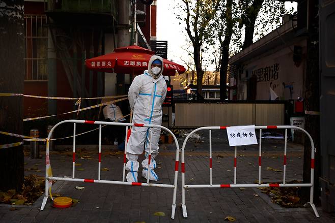 11월 25일 중국 베이징의 한 주거단지가 코로나19 바이러스 발생으로 봉쇄된 가운데 방호복을 입은 한 공무원이 입구에서 경비를 서고 있다./로이터 연합뉴스