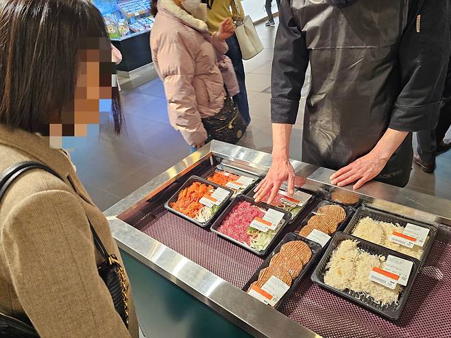 28일 오후 8시쯤 서울 한 대형 백화점 식품관에서 1만5000원~2만원대 불고기, 돈가스, 떡갈비 밀키트를 모두 1만원에 판매하는 업주와 손님이 대화를 나누고 있다. /조연우 기자