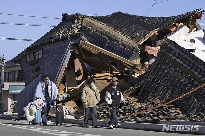 [와지마=AP/뉴시스]일본 이시카와현 노토반도에서 지진이 일어난 지 1일로 3개월이 된 가운데, 여전히 집에 돌아가지 못하고 피난 생활을 하는 이재민이 8000명을 넘는 것으로 알려졌다. 지난 1월2일 일본 이시카와현 와지마시에서 소지품을 꾸린 한 가족이 전날 노토반도에서 발생한 지진으로 무너진 한 가옥 앞을 지나가고 있다. 2024.04.01.