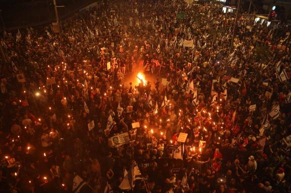 이스라엘 시민 수만명이 30일(현지시간) 텔아비브에 있는 국방부 앞에서 팔레스타인 무장정파 하마스가 가자지구에서 억류 중인 인질의 석방과 베냐민 네타냐후 총리의 사퇴를 요구하는 시위를 벌이고 있다. 시위대가 네타냐후 총리의 전쟁 정책을 비판하며 불을 피우고 도로를 봉쇄하자 경찰이 강제로 해산을 시도하면서 충돌이 발생했다. 텔아비브 AFP 연합뉴스