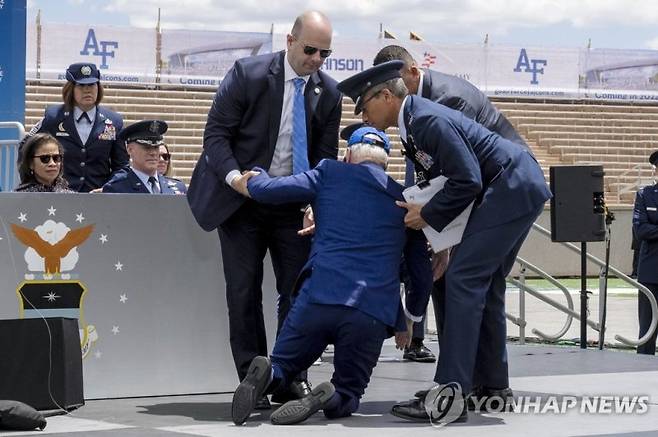 지난해 6월1일(현지시간) 미국 콜로라도주 콜로라도스프링스의 미국 공군 사관학교 졸업식에 참석한 조 바이든 대통령이 무대에서 넘어지자 부축을 받고 있다.AP연합뉴스