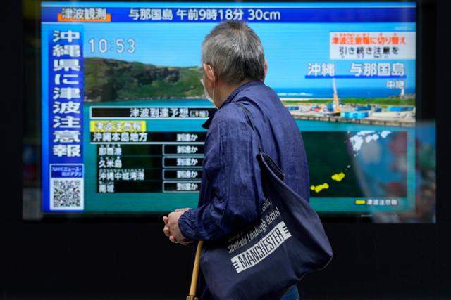 일본 도쿄의 한 시민이 3일 시내 한 TV에서 나오는 오키나와 지역 쓰나미(해일) 관련 뉴스를 보고 있다. 도쿄=AP 연합뉴스