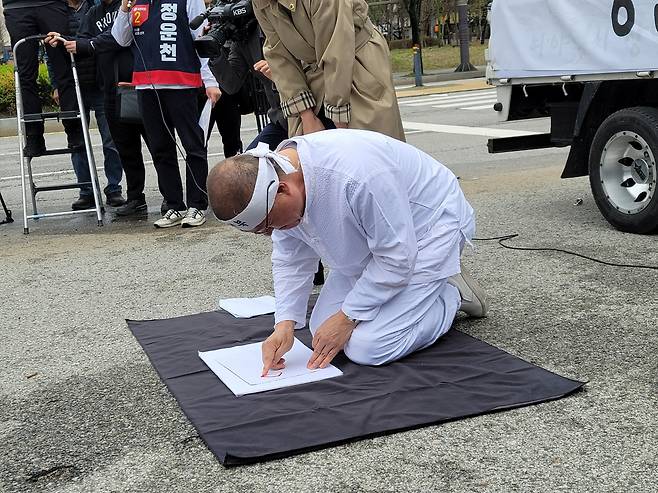 전북 전주시을 선거구에 출마한 정운천 후보가 전북특별자치도청 앞에서 전주 시민들의 지지를 호소하며 혈서를 쓰고 있다.[정운천 의원실 제공]