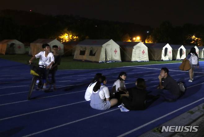 [화롄=AP/뉴시스] 3일(현지시각) 대만 동부 화롄시에서 발생한 강진 이후 집에서 대피한 주민들이 대피소 텐트 주변에 모여 앉아 있다. 2024.04.04.