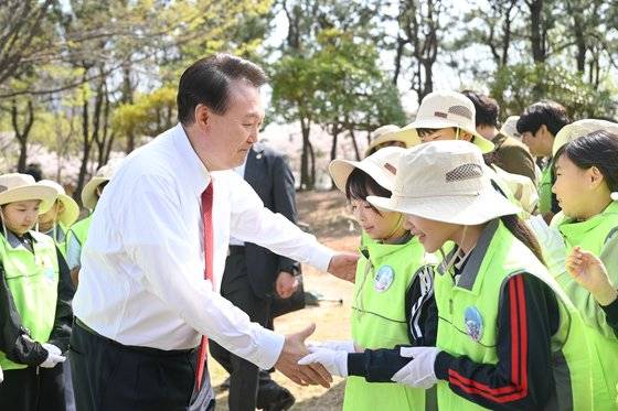 윤석열 대통령이 5일 오후 식목일 기념행사를 마친 후 부산 강서구 명지 유아숲체험원에서 우리나라 특산식물인 미선나무를 심은 뒤 부산 남명초등학교 5학년 학생들과 악수하고 있다. 사진 대통령실