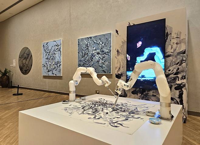 홍콩 침사추이의 문화예술 복합쇼핑몰 K11 뮤제아에서 캐나다 태생의 홍콩계 신진 작가 수웬 청이 선보인 인공지능(AI) 아트 작품. AI 로봇(앞)과 협업한 회화 작품들이 벽면에 전시돼 있다.