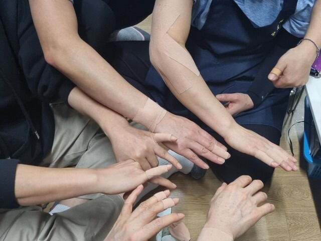 서울대학교 학생회관 식당 조리노동자들이 모여 팔 곳곳에 붙인 파스를 내보이고 있다. 서울대 학생회관 식당 조리노동자 제공