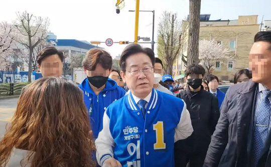 이재명 더불어민주당 대표가 7일 오전 인천 계양구에서 유세를 하다가 부딪힌 허리를 만지며 행인을 쳐다보고 있다. 유튜브 ‘이재명’ 채널 라이브 방송 캡처