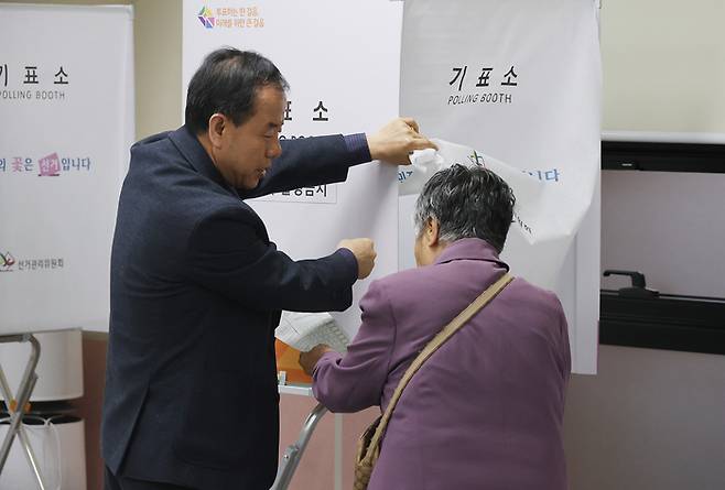 제22대 국회의원 선거 사전투표 첫날인 5일 제주시 삼도1동주민센터에 마련된 사전투표소에서 한 할머니가 투표사무원으로부터 사전투표 안내를 받고 있다. [연합뉴스]