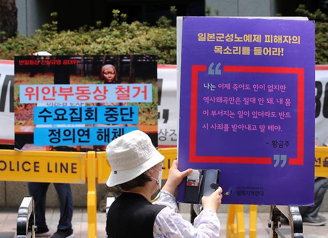 22일 서울 종로구 옛 일본대사관 인근에서 열린 제1549차 일본군 성노예제 문제 해결을 위한 정기 수요시위에서 참가자 너머로 반대 집회 문구가 보이고 있다. 2022.6.22/뉴스1