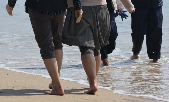 지난 7일 부산 해운대구 송정해수욕장을 찾은 시민들이 맨발로 바닷가를 걷고 있다. 송봉근 기자