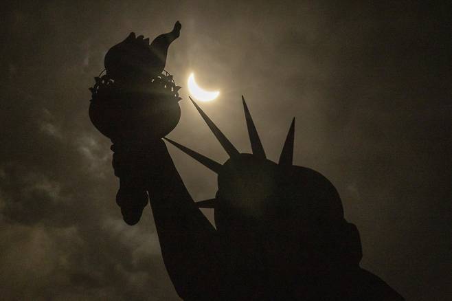 [뉴욕=AP/뉴시스] 8일(현지시각) 미국 뉴욕의 자유의 여신상 상공에서 달이 태양을 완전히 가리는 개기일식이 진행되고 있다. 2024.04.09.