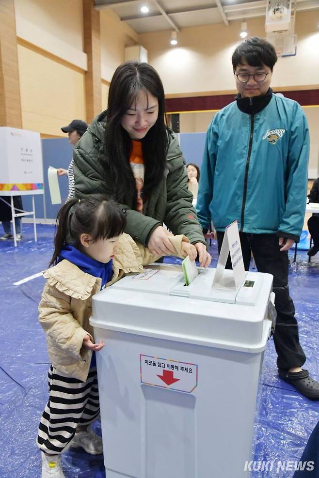 제22대 국회의원 선거일인 10일 서울 송파구 덕수고에 마련한 위례제3투표소에서한 유권자가 아이와 투표하고 있다.
