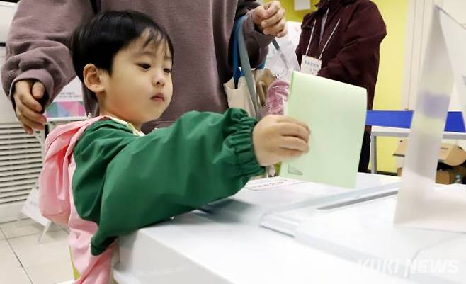 제22대 국회의원 선거일인 10일 서울 대방중학에 마련한 대방제5투표소에서 한 어린이가 투표용지를 투표함에 넣고 있다.