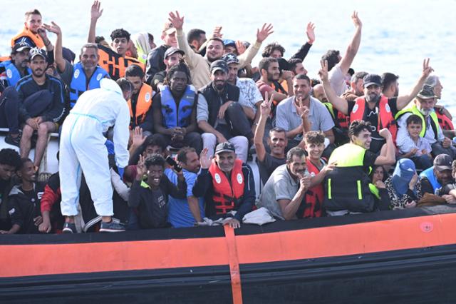 지난해 9월 이탈리아 람페두사 항구에 도착하는 이탈리아 해안경비대 순찰선 위에 바다를 건너온 이민자들이 탑승한 채 손을 흔들고 있다. 람페두사=EPA 연합뉴스