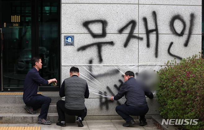 [서울=뉴시스] 김명년 기자 = 11일 오후 서울 서초동 서울고등검찰청 건물에 문재인 전 대통령과 서훈 전 국가정보원장을 비방하는 내용의 낙서를 하고 건물 창문에 돌을 던진 40대 남성이 경찰에 붙잡혔다. 사건 현장에서 청사 관계자들이 비닐막으로 낙서를 가리고 있다. 2024.04.11. kmn@newsis.com
