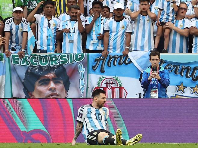 22일(현지시간) 카타르 루사일 스타디움에서 열린 2022 카타르 월드컵 조별리그 C조 1차전 아르헨티나와 사우디아라비아 경기. 아르헨티나의 리오넬 메시가 후반 1-2로 지고 있는 상황에서 공격 뒤 그라운드에 주저앉아 있다. 메시 뒤로 마라도나의 사진이 걸려 있다./연합뉴스