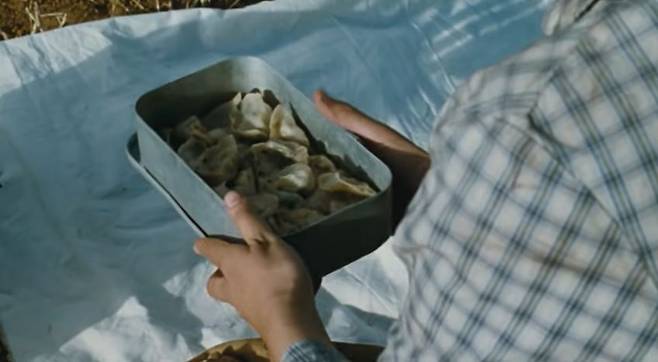 중국 영화 ‘인생’의 한 장면. 공리가 연기한 부귀의 부인 자전이 싸 둔 만두 도시락을 먹지도 못하고 아들 유칭이 트럭 사고로 사망한다. 이에 유칭의 무덤 앞에 자전이 새 만두를 놓아주는 모습. [유튜브 캡처]