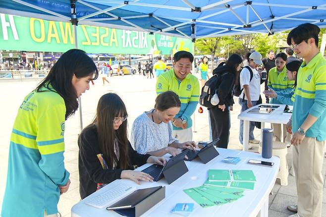 부산에서 열린 거리 캠페인에 동참한 시민들이 ASEZ WAO에 지지를 보내며 1인 1그루 나무심기 온라인 서명에 참여하고 있다.