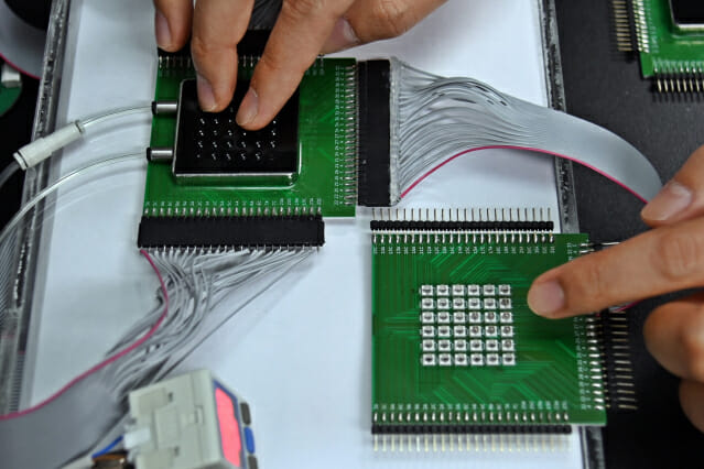 ETRI가 개발한 입체화 촉각 디스플레이에서 생성된 입체 형상을 손으로 느끼는 모습(왼쪽)과  LED 기판.