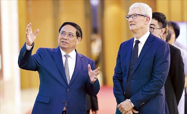 < 팜민찐 총리·팀 쿡 ‘화기애애’ >  베트남을 방문 중인 팀 쿡 애플 최고경영자(CEO·오른쪽)가 16일 하노이 정부청사에서 팜민찐 베트남 총리와 이야기를 나누고 있다. 중국 공급망 의존도를 낮추는 방안을 모색하고 있는 쿡 CEO는 이날 베트남 공급망에 대한 투자 확대 계획을 밝혔다.  AP연합뉴스