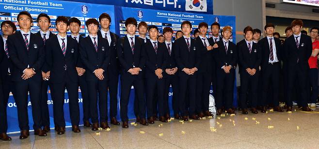 South Korean national soccer team players look at sticky yeot candy thrown by angry football fans at Incheon Airport after their return from the World Cup in Brazil, June 30, 2014. (Herald DB)