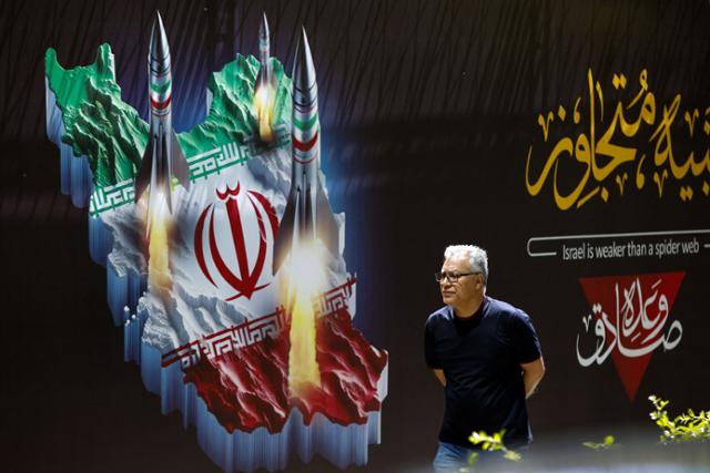 한 이란 남성이 19일 수도 테헤란의 한 거리에서 이란 국기와 미사일이 그려진 '반(反)이스라엘' 현수막 앞을 지나가고 있다. 테헤란=AFP 연합뉴스