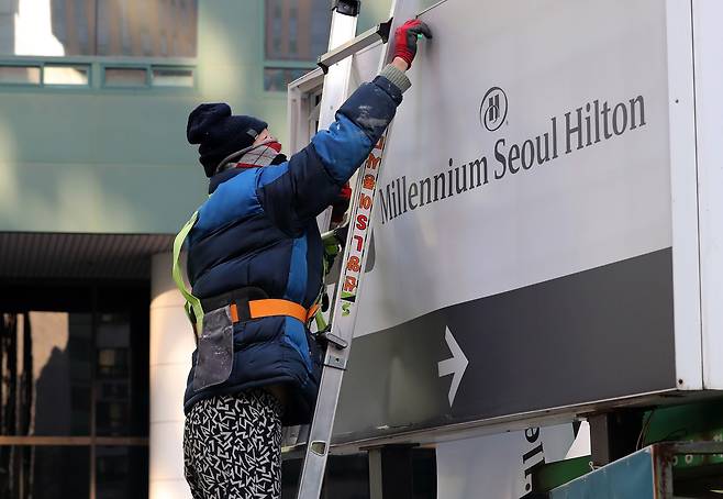 지난해 1월 1일 서울 중구 밀레니엄 힐튼 서울에서 관계자가 호텔 주차장 안내판을 떼어내고 있다. 밀레니엄 힐튼 서울은 2022년 12월 31일 영업을 종료했다. /뉴스1
