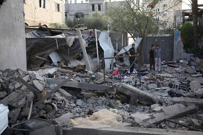 팔레스타인 난민들이 24일(현지시간) 가자지구 남부 도시 라파에서 파괴된 집 잔해 사이에 서 있다.(사진=신화연합뉴스)