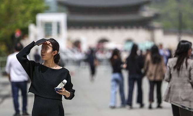 초여름 날씨를 보인 26일 서울 종로구 광화문광장에서 한 시민이 손으로 햇빛을 가린 채 이동하고 있다. 뉴시스