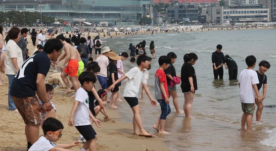 부산 낮 최고기온이 24도를 기록하는 등 초여름 날씨를 보인 28일 부산 해운대해수욕장을 찾은 시민과 외국인 관광객들이 선템과 물놀이를 하며 이른 더위를 식히고 있다. 송봉근 기자