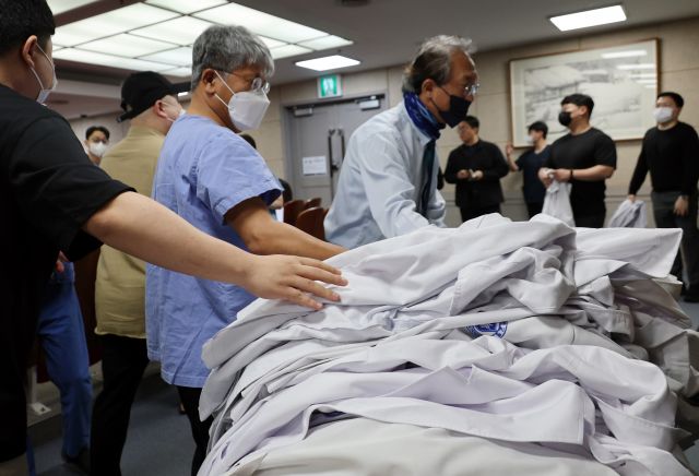 29일 오전 전북 익산 원광대학교병원 대강당에서 교수들이 사직서를 제출한 뒤 가운을 두고 떠나고 있다. 연합뉴스