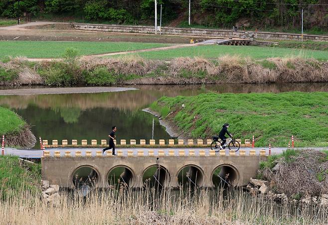 현대식으로 지은 강매세월교 위로 시민들이 달리거나 자전거를 탄 채 건너고 있다. 위쪽에 강매석교가 보인다. 한겨레21
