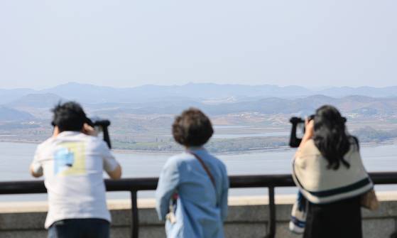 South Koreans peer across the Imjin River into North Korea from an observatory near the inter-Korean border in Paju, Gyeonggi, on April 14. [YONHAP]