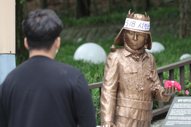 ▲ 광주 남구 광주공원에 5·18 시민군을 상징하는 김군 동상을 지나가는 시민이 바라보고 있다. ⓒ연합뉴스