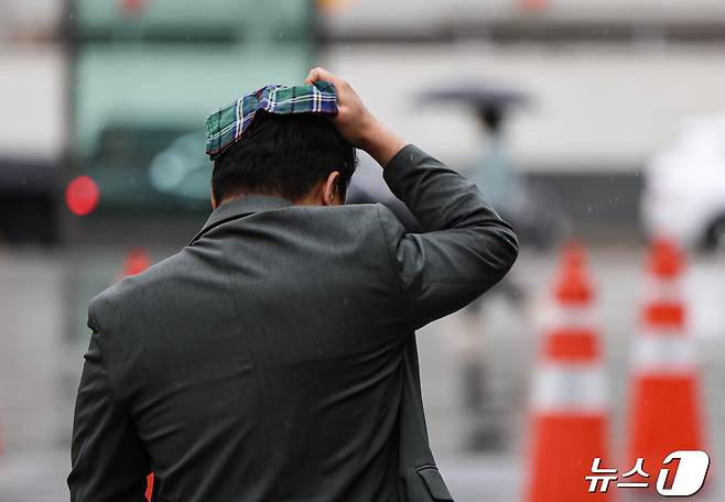 전국 대부분 지역에 비가 예보된 24일 오전 서울 종로구 광화문광장에서 한 시민이 손수건으로 머리를 가리며 발걸음을 옮기고 있다. 2024.4.24/뉴스1 ⓒ News1 김도우 기자